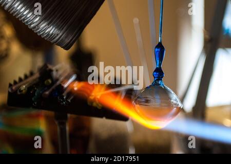 Ein Glasmeister erstellen ein Glasstück mit einem typischen Flamme für Glasbläserei Stockfoto