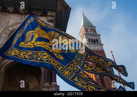 VENEDIG, ITALIEN - 25. APRIL 2018: Unter dem Campanile von San Marco fliegt eine Flagge Venedigs Stockfoto