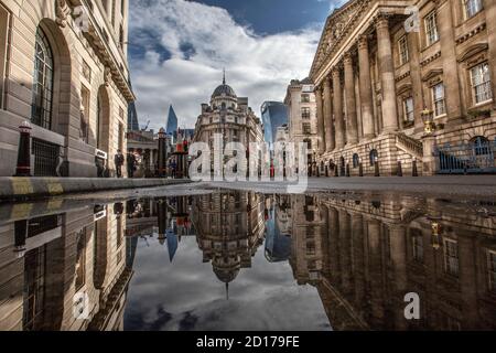 Bank of England und Royal Exchange Area im Herzen des Finanzviertels in der City of London spiegelt sich in einer Pfütze auf Threadneedle Street, London. Stockfoto