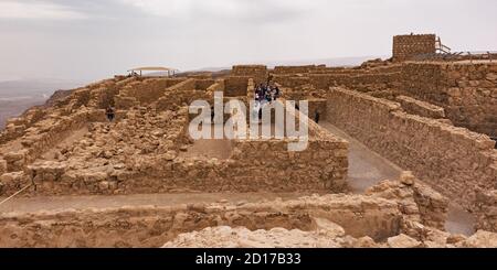 Touristen in den Lagerräumen Komplex auf der Nordwestseite von masada in israel mit Wachturm und Badehaus Das Recht und Sturmwolken in der Stockfoto