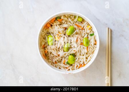 Nehmen Sie gekochten gedämpften Basmati-Reis mit Edamame-Bohnen in Kunststoff-Cup Box Container. Traditionelle Gesunde Bio-Lebensmittel. Stockfoto