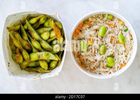 Nehmen Sie gekochten gedämpften Basmati-Reis mit Edamame Bohnen und Gemüse in Kunststoff-Box Verpackung Container. Traditionelles Essen. Stockfoto