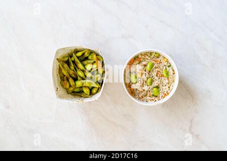 Nehmen Sie gekochten gedämpften Basmati-Reis mit Edamame Bohnen und Gemüse in Kunststoff-Box Verpackung Container. Traditionelles Essen. Stockfoto