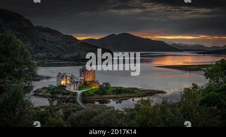 Aufgenommen bei Sonnenuntergang, ein Foto von Eilean Donan Castle im schottischen Hochland. Die Burg ist im Licht der Lichter erleuchtet Stockfoto