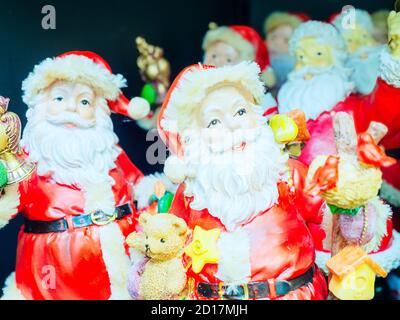 Dekorative Figur des Weihnachtsmanns mit Geschenken auf dem Hintergrund anderer Figuren. Nahaufnahme mit Fokus im Vordergrund Stockfoto