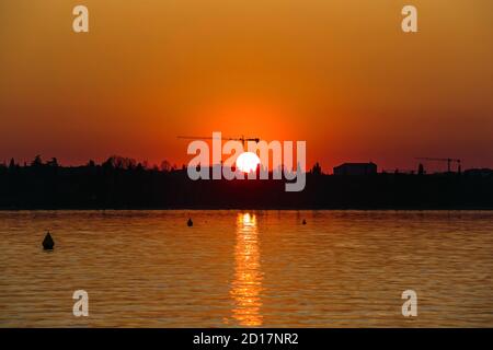 Zauberhafter Sonnenuntergang mit der Sonne hinter einem Turmstock in der Nähe von Gardasee, Peschiera del Garda, Venetien, Italien Stockfoto