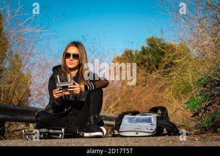 Junge moderne Frau Vorbereitung für Luftaufnahmen. Fliegende Drohne im sonnigen Herbsttag. Outdoor-Hobby Stockfoto