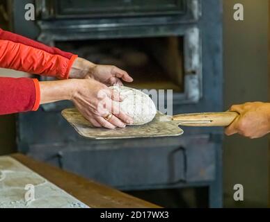 Walliser Roggenbrot-Backwerkstatt in Goppenstein-Erschmatt, Schweiz. In den Ofen. Bei etwa 300 Grad Celsius werden die Roggenbrote gebacken