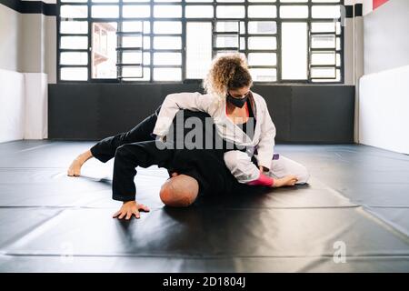 Mann und Frau trainieren Kampfkünste und Judo mit Kimonos Auf der Turnhalle Bodenmatte mit einer Gesichtsmaske, weil Der covid 19 Coronavirus Pandemie Stockfoto