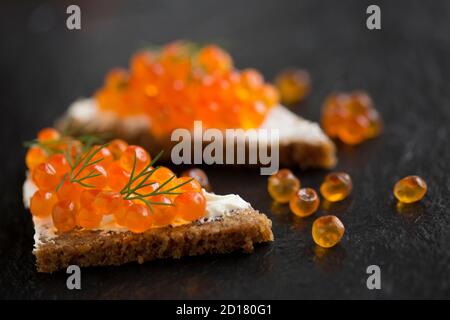 Pazifischer Lachskaviar, gekauft aus einem Supermarkt, serviert auf Roggenbrot mit Frischkäse und garniert mit frischem Dill. Dorset England GB Stockfoto