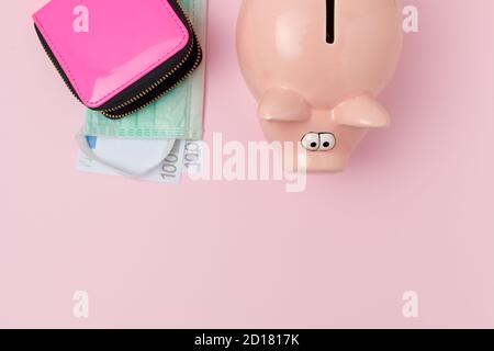 Coronavirus flach lag mit Sparschwein, Brieftasche, Euro-Geld und medizinische Maske auf rosa Hintergrund. Stockfoto