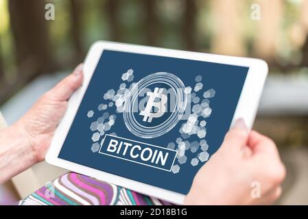 Weibliche Hände halten ein Tablet mit Bitcoin-Konzept Stockfoto