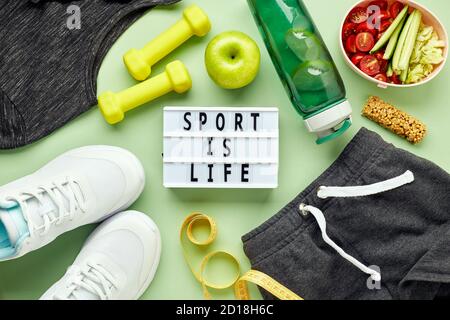 Kreative flache Lay von Sport- und Fitnessgeräten und Lightbox mit Sport-Slogan. Weiße Damen Sneaker, Wasserflasche, Sportbekleidung, Hanteln und lun Stockfoto