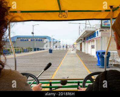 Blick von der Rückseite eines viersitzigen Fahrrads auf Der Wildwood Boardwalk ist zwischen zwei Personen Stockfoto