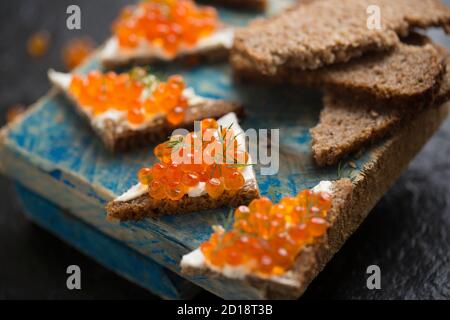 Pazifischer Lachskaviar, gekauft aus einem Supermarkt, serviert auf Roggenbrot mit Frischkäse und garniert mit frischem Dill. Dorset England GB Stockfoto