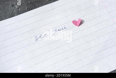 Siehe Sie notieren Hand auf einem Papier geschrieben. Liebesbrief mit Papier Herz. Beziehungskonzept. Abstand Beziehung oder lange Abschied. Fehlende Liebe oder Partner. Romantische Erinnerung Stockfoto