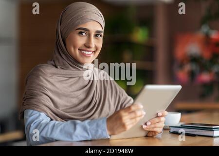 Schöne arabische Frau sitzt im Café, mit digitalen Tablet Stockfoto