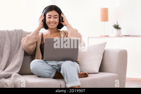 Asiatische Dame, die Musik mit kabellosen Kopfhörern hört Stockfoto