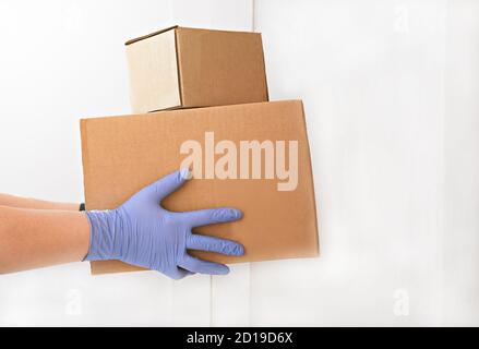 Kurier liefert Boxen. Hände halten Box mit Lebensmitteln. Kontaktloses Zustellkonzept. Halten soziale Distanz und zu Hause bleiben während Quarantäne. Kontakt frei und sicher einkaufen Stockfoto