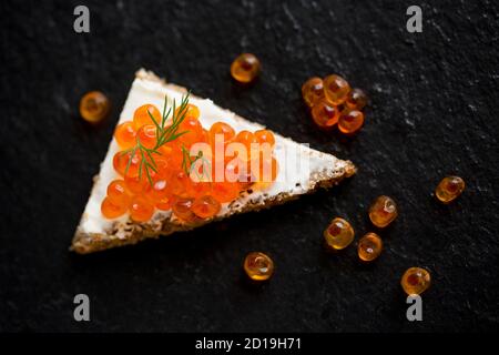 Pazifischer Lachskaviar, gekauft aus einem Supermarkt, serviert auf Roggenbrot mit Frischkäse und garniert mit frischem Dill. Dorset England GB Stockfoto