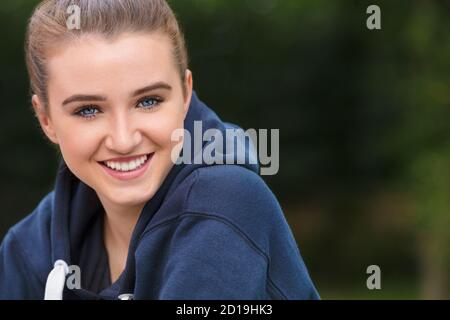 Schöne Mädchen Teenager weibliche junge Frau mit blauen Augen draußen Dunkelblauer Kapuzenpullover, fröhlich und lächelnd mit perfekten Zähnen Stockfoto