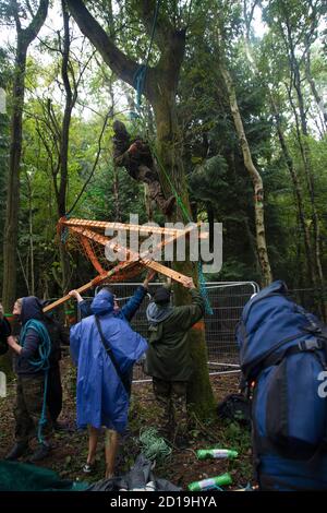 Cubbbington Woods, Warwickshire, Großbritannien. Oktober 2020. In den frühen Morgenstunden des 5. Okt. 2020 ergreifen friedliche HS2-Demonstranten Maßnahmen zum Schutz der Eichen und alten Wälder, die für die Zerstörung in Cubbbington Woods, Warwickshire, Großbritannien, markiert sind. Zwei Kletterer erklimmen Bäume und versuchen, ein Nest mit einer Holzkonstruktion mit einem Rahmen und einem Netz zu bauen. Einmal in den Bäumen Abriss müsste aufhören, bis die Demonstranten wurden entfernt Kredit: Denise Laura Baker/Alamy Live News Stockfoto