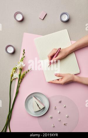Minimale Zusammensetzung der weiblichen Hände schriftlich in leeren Planer über rosa Grafik Hintergrund mit floralen Dekor, Kopierer Raum Stockfoto