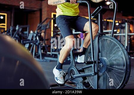 Kurzer Schuss von athletischen Mann in Sportbekleidung tun Radfahren auf Ergometer im Fitnessstudio, Cardio-Training Stockfoto