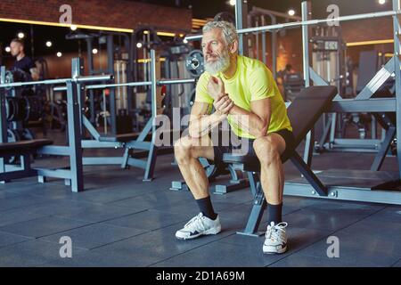 Eine Pause einlegen. Erschöpfter reifer Mann in Sportswear, der nach hartem Training im Fitnessstudio ruht Stockfoto