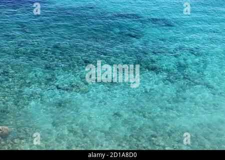Azure Wasser Textur, transparente Meeresoberfläche mit einem felsigen Boden. Luftaufnahme, natürlicher blauer Hintergrund Stockfoto
