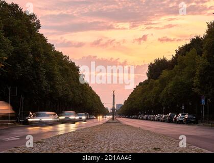 Straße durch den Tiergarten Park mit Bewegung verschwommen Autos und Berlins Siegessäule im Hintergrund bei Sonnenuntergang Berlin Stockfoto