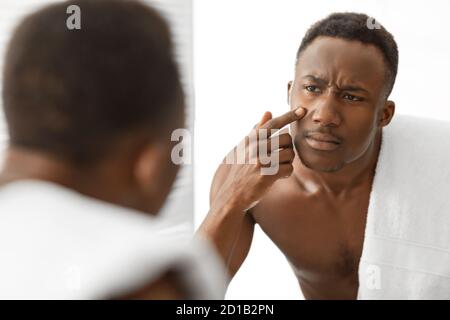 Afrikanischer Mann Berührt Akne Pickel Auf Gesicht Stehend Im Badezimmer Stockfoto