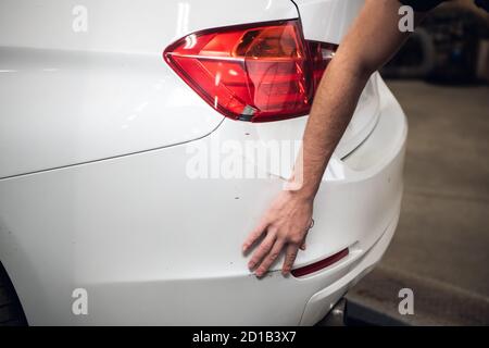 Man untersucht einen zerkratzten Stoßfänger und einen defekten Scheinwerfer Stockfoto