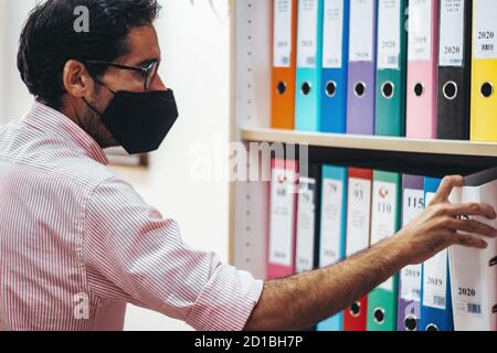 Personen, die in einem Beraterbüro mit und ohne Maske arbeiten Stockfoto