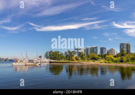 Die Uferpromenade in Vancouver, BC. Der Blick auf die Wolkenkratzer in der Innenstadt und Yachten/Segelboote, die am Stanley Park angedockt sind. Blauer Himmel mit streifenden Wolken. Stockfoto