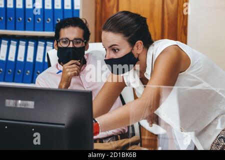 Personen, die in einem Beraterbüro mit und ohne Maske arbeiten Stockfoto