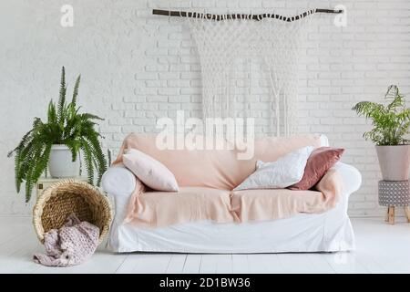Gemütliches Wohnzimmer Interieur von weißen Couch und zwei vas E von Zimmerpflanzen auf dem Hintergrund der weißen Ziegel Wand und bemalter Holzboden Stockfoto