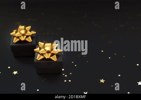 Nahaufnahme von zwei schwarzen Schachteln mit Geschenken auf schwarzem Hintergrund mit goldenen Sternen. Black Friday super Sale.Selective Fokus Stockfoto