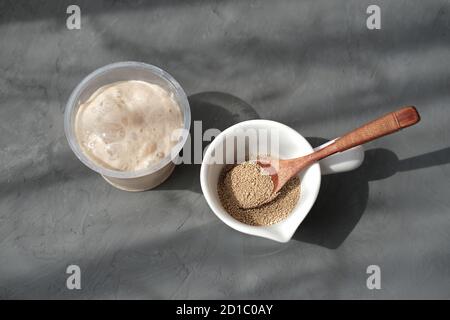 Nährhefe in Flocken und in aktiver Form. Sauerteig Starter in einem Behälter. Brot zu Hause machen. Hausgemachter Teig Starter. Koch- und Backkonzept. Draufsicht Stockfoto