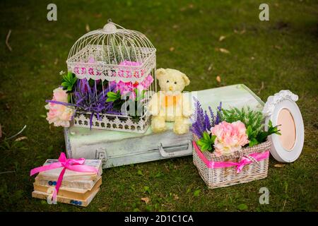 Straßendekorationen für eine Kinderparty. Retro Koffer mit Blumen mit einem Teddybären in einem grünen Park. Party auf der Straße. Stockfoto