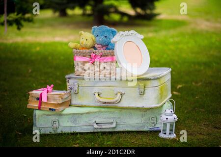 Straßendekorationen für eine Kinderparty. Retro Koffer mit Blumen mit einem Teddybären in einem grünen Park. Party auf der Straße. Stockfoto