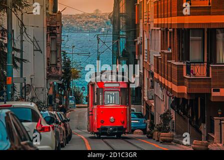 Alte nostalgische Straßenbahn, die durch die Straßen des Kadikoy-Viertels auf der asiatischen Seite Istanbuls fährt. Das trendige Viertel ist voller farbenfroher Gebäude. Marmarameer. Stockfoto