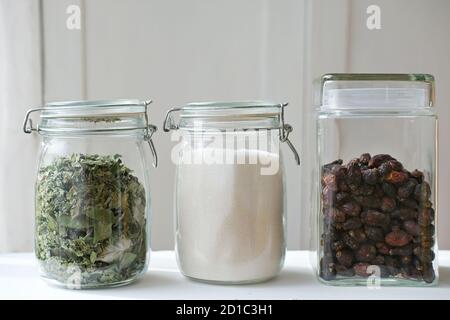 Glas Gläser für die Küche Lebensmittelgeschäft Lagerung. Zucker, Kräuter und Hagebutten Beeren in Gläsern. Bestellen Sie in den Regalen und umweltfreundliche Lagerung. Stockfoto