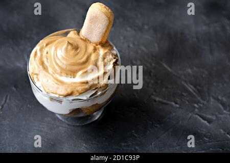 Iced schaumig Dalgona Kaffee Tiramisu, ein trendiges flauschig cremig Schlagkaffee Dessert. Tiramisu mit koreanischem Getränk. Latte Espresso Dessert mit Kaffee Schaum. Schlagsahne Dessert auf grauem Hintergrund Stockfoto