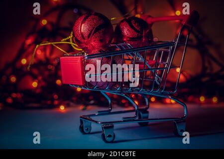 Warenkorb mit roten Weihnachtskugeln Nahaufnahme auf dem Hintergrund der Weihnachtsbeleuchtung. Schöne Weihnachten Hintergrund Stockfoto