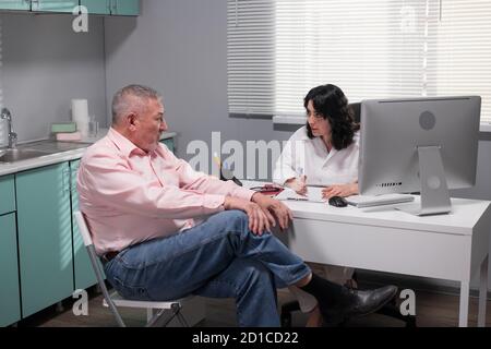 Eine Praktikerin, die ihrem Patienten die Behandlungsmaßnahmen erklärt. Stockfoto