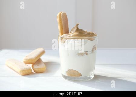 Iced schaumig Dalgona Coffee Tiramisu, ein trendiger flauschiger cremiger Schlagkaffee auf der Oberseite des Tiramisu Dessert. Koreanische Getränk Latte Espresso mit Kaffee Schaum. Savoyardi Bisquits für die Dekoration. Stockfoto