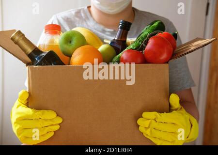 Sicheres Einkaufen bei Pandemie. Kurier trägt Gesichtsmaske und Handschuhe liefern Lebensmittelbestellung in Coronavirus-Epidemie. Lebensmittellieferung während des Corona-Virus-Ausbruchs. Essen zum Mitnehmen. Menschen lagern Lebensmittel ein. Stockfoto