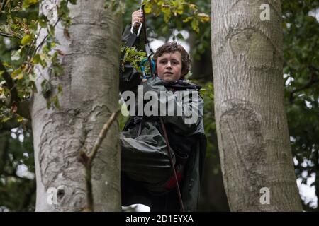 Aylesbury Vale, Großbritannien. Oktober 2020. Ein junger Baumschützer klettert in einem Wildschutzlager in einem alten Waldgebiet am JonesÕ Hill Wood auf ein Baumhaus über 60 Meter über dem Boden. Das Camp JonesÕ Hill Wood, eines von mehreren Protestcamps, das von Anti-HS2-Aktivisten entlang der Strecke der 106 Mrd. £schweren HS2-Hochgeschwindigkeitsstrecke errichtet wurde, um dem umstrittenen Infrastrukturprojekt zu widerstehen, wird derzeit von den Gerichtsvollziehern des National Evction Teams, die im Auftrag der HS2 Ltd. Arbeiten, vertrieben. Quelle: Mark Kerrison/Alamy Live News Stockfoto