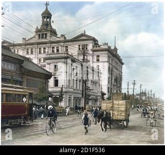 Kolorierte Ansicht einer Straßenszene mit verschiedenen Verkehrsmitteln vor dem Mitsukoshi Kaufhaus (mit Turm) in Nihonbashi, einem Geschäftsviertel in Chuo, Tokio, Japan, 1922. (Foto von Burton Holmes) Stockfoto